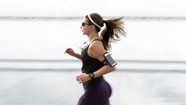 Woman running in sunglasses wearing a fitness tracker