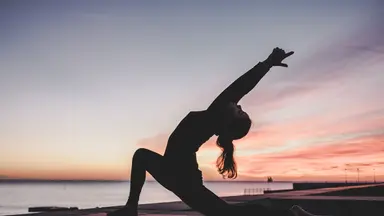 Women practicing yoga in front of sunset
