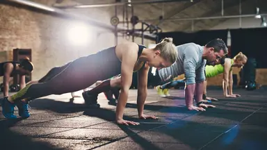 Fit women and men planking in a fitness class.