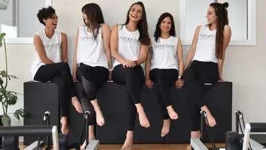 The staff of Flex and Flow Pilates joking together in the exercise room