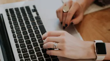 woman typing on laptop with apple watch