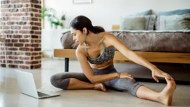 Woman stretching in workout clothes in front of a computer