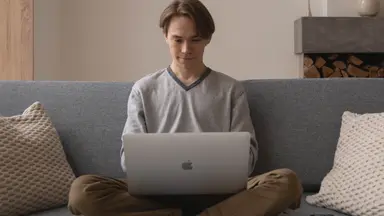 Person on a couch working on a laptop