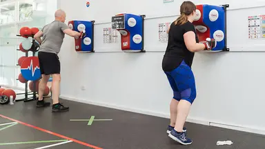 A man and a woman using a punching bag at HighLow Fitness