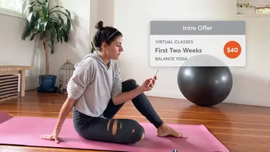 Woman on yoga mat purchases a fitness introductory offer on Mindbody