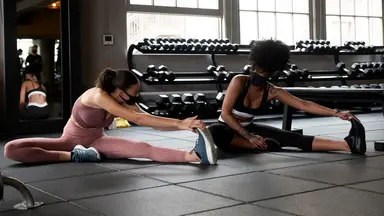 two women in masks working out in fitness studio