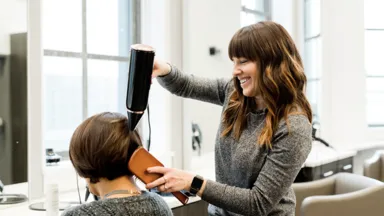 female hair stylist blow drying hair in salon