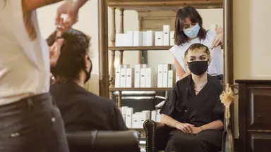 woman in mask getting hair done at salon