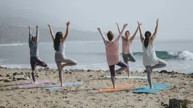group of women doing yoga on beach