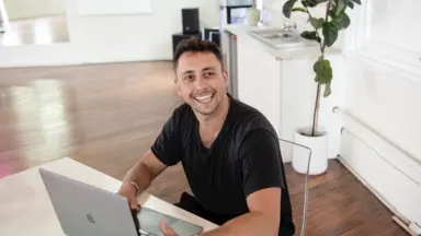 Man smiling at laptop in dance studio