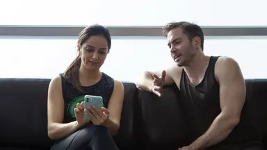 woman showing man phone on couch