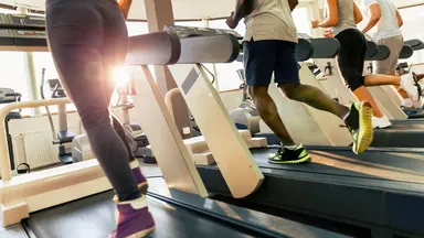 Four people running on treadmills at a gym