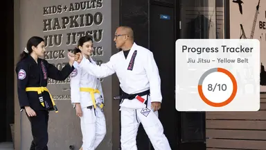 Martial arts teacher coaching two kids with a progress tracker visual