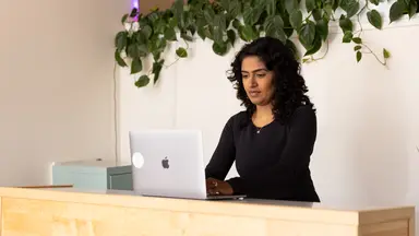 woman standing at desk using laptop