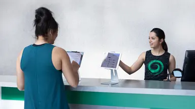 Women checks into fitness studio using iPad.