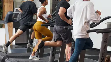 Four people run on treadmills next to each other.