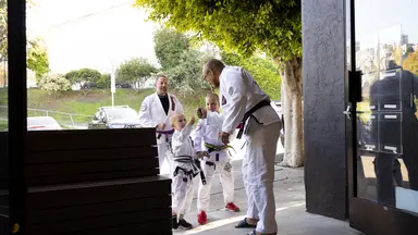 Young students greeting their instructor outside a martial arts academy