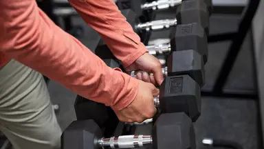 man in gym grabbing weights