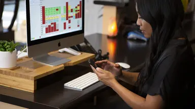 woman sitting at desk working on her phone