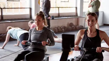 Two women work out on rower machines