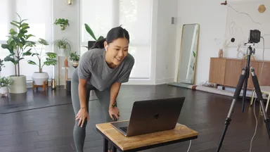 woman looking at laptop teaching yoga class