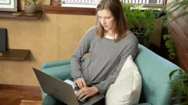 A woman sitting in a chair, using a laptop