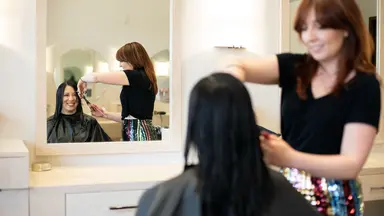 A stylist trims a customer's hair.
