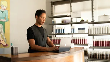 Spa business owner behind front desk working on laptop