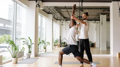 A man practicing yoga with an instructor 