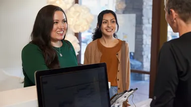 2 customers and an employee at the front desk