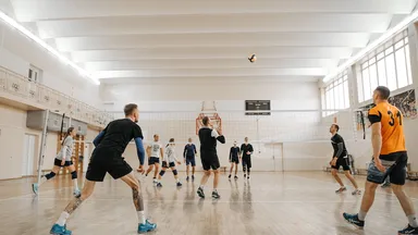A group of people playing volleyball at a sports facility.