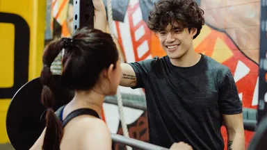 Two people talking at the gym.