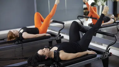 Two women using Pilates reformers.