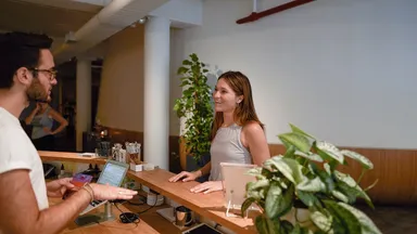 An employee at the front desk talking to a customer.