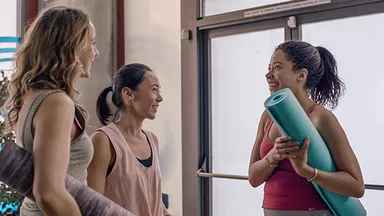 People holding yoga mats talking in entryway