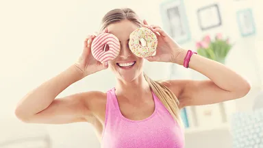 woman holding donuts to her eyes
