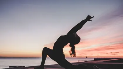 Women practicing yoga in front of sunset