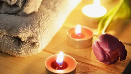 Candles and rose by folded towels