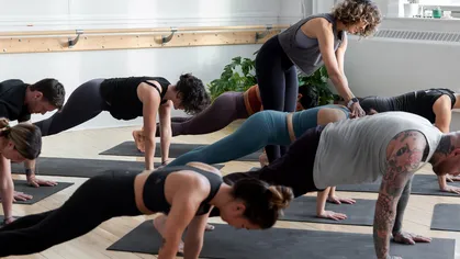 female yoga instructor adjusting students in yoga class