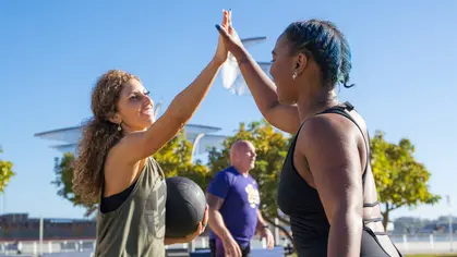 Two women high-fiving after a workout