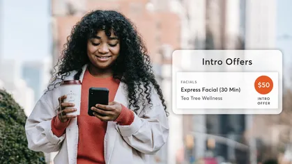 woman walking with coffee on smartphone booking fitness class