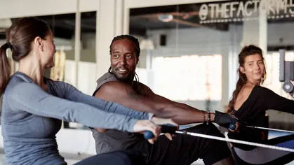 two women and one man on rowing machine at gym
