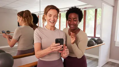Two people looking at a phone in a barre studio