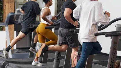 Four people running on the treadmill at the gym.
