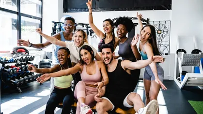 Eight people smiling posing for a picture at a gym