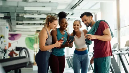 4 people looking at a phone at a gym