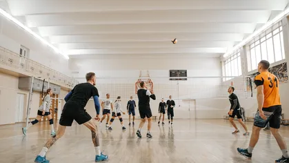 A group of people playing volleyball at a sports facility.