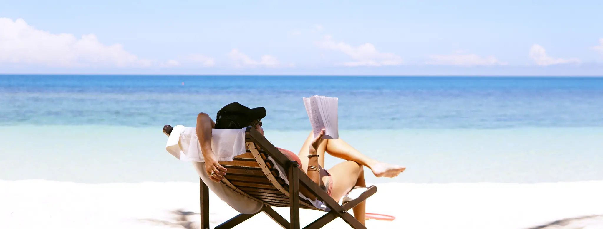 Woman reading a book on the beach in a chair