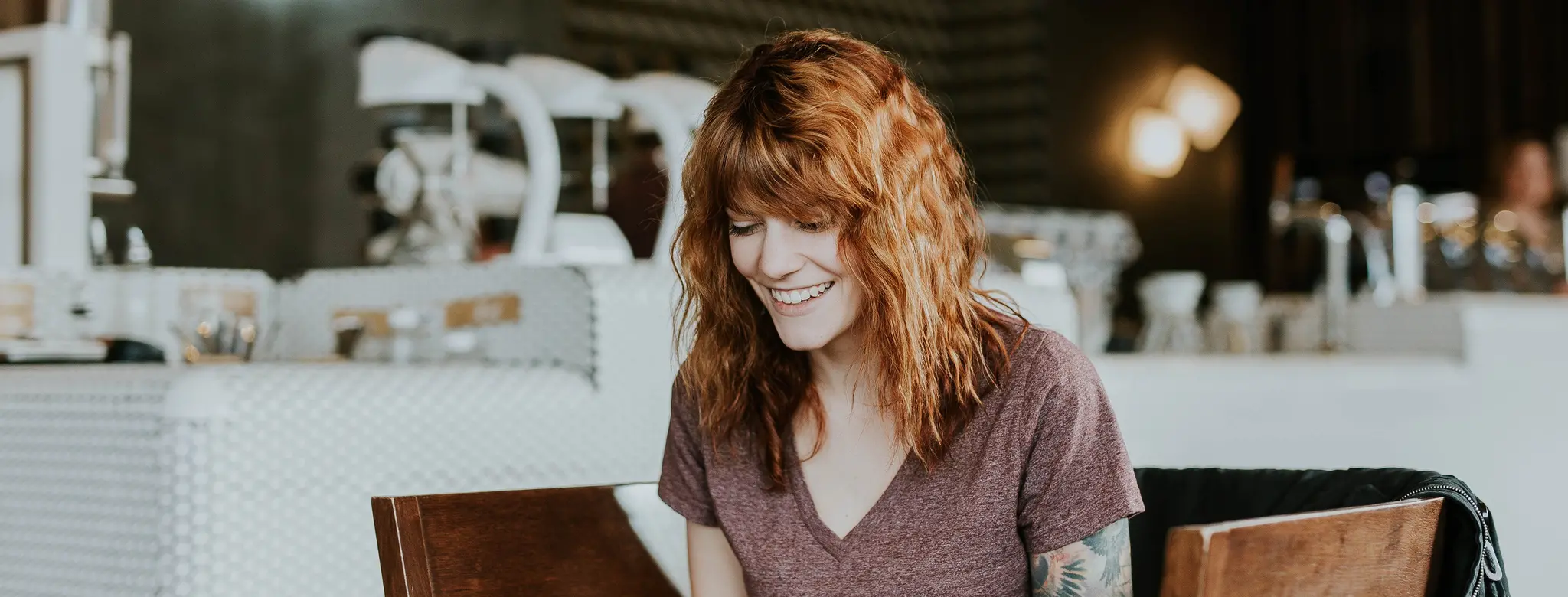 woman with red hair in coffee shop on laptop