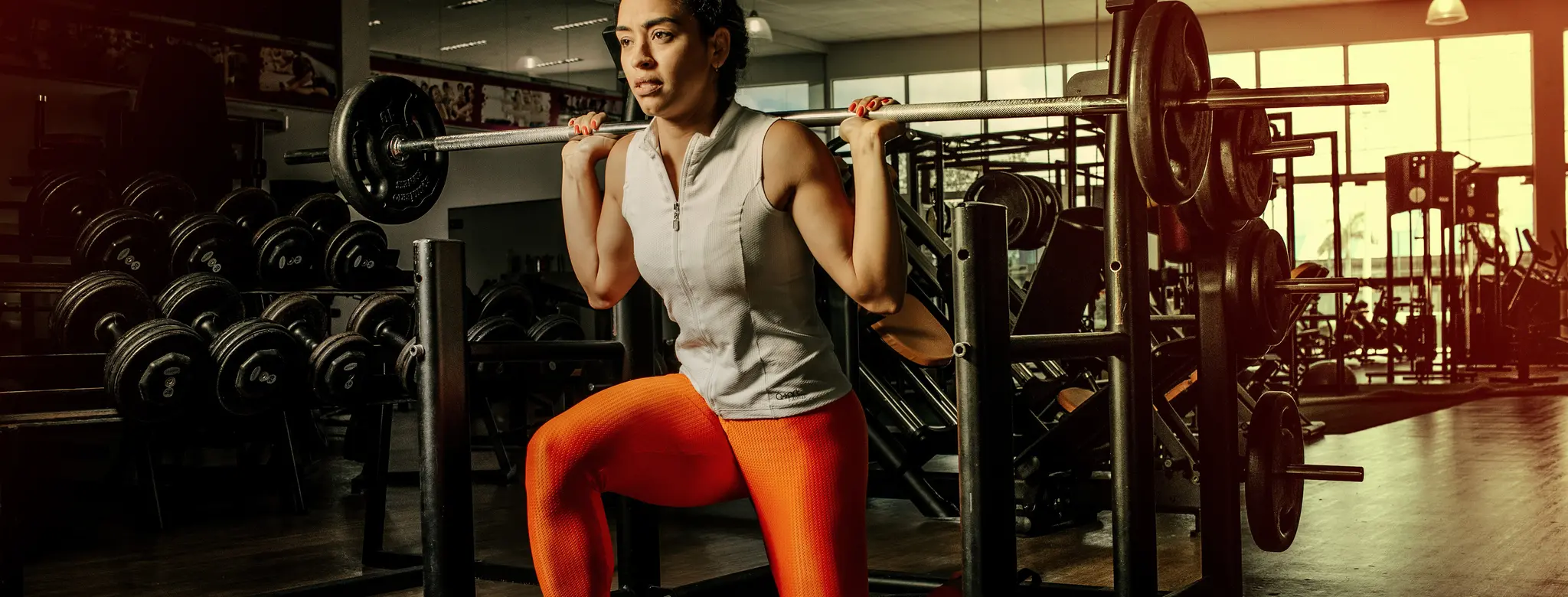 woman in orange pants lifting weights at gym